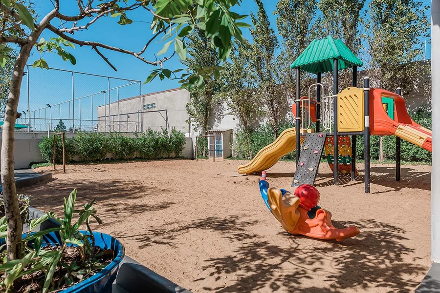 Área externa da unidade Kids do Múltiplo, com playground de madeira, escorregador e areia