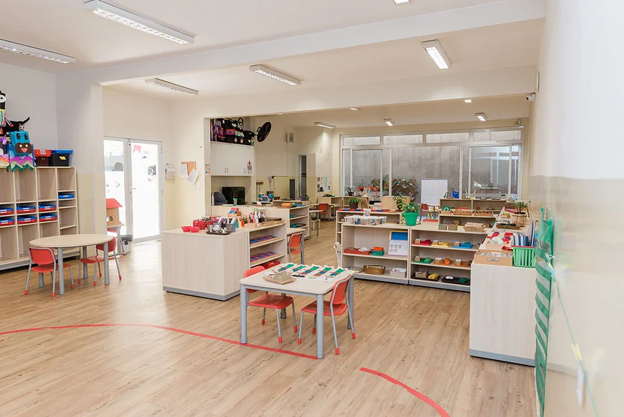 Sala de atividades da unidade Kids do Múltiplo, com bancadas, prateleiras de material e mesa central