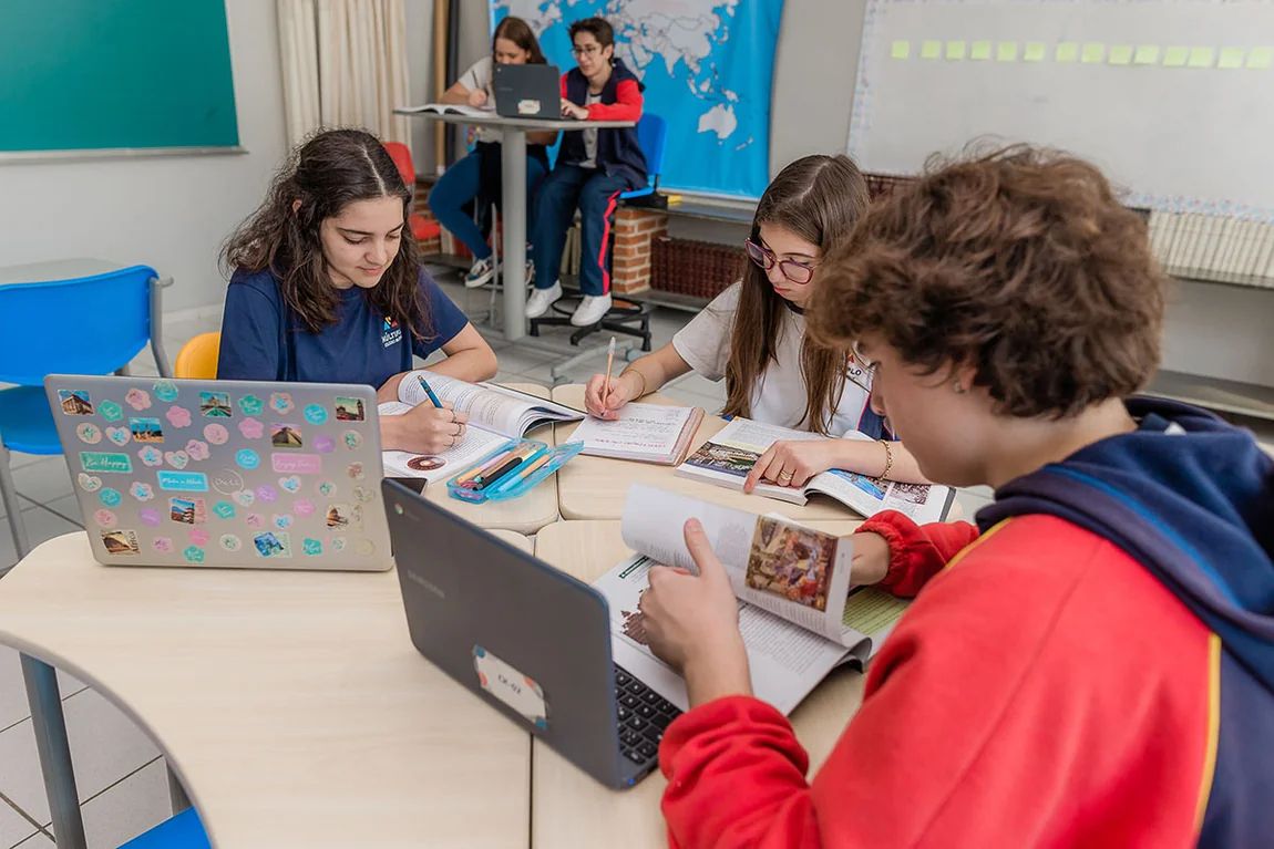 Alunos do Fundamental Anos Finais do Múltiplo estudando em grupo com notebooks sobre a mesa