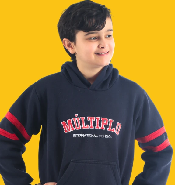 Aluno do Fundamental Anos Finais do Múltiplo International School de moletom da escola, sorrindo, sobre fundo amarelo
