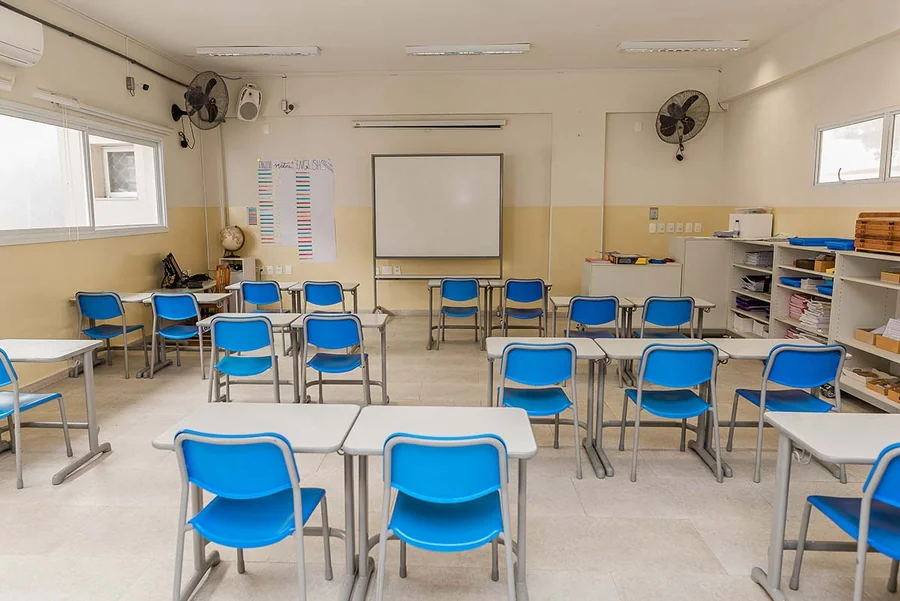 Sala de aula do Fundamental Anos Finais do Múltiplo, com carteiras azuis e lousa branca