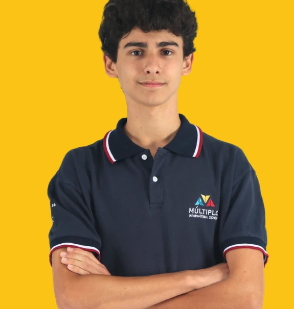 Aluno do Ensino Médio do Múltiplo International School de uniforme, de braços cruzados, sobre fundo amarelo