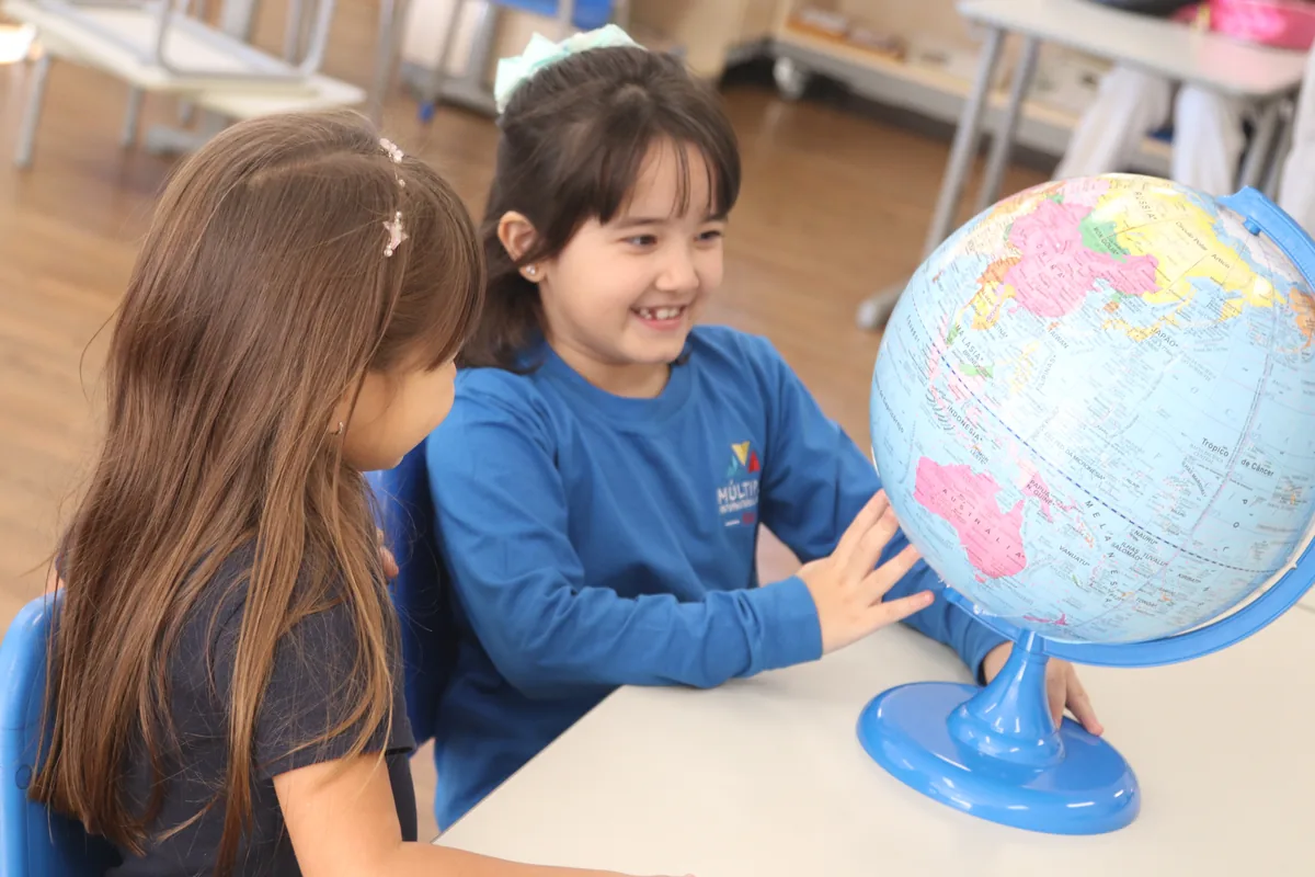 Alunas do Múltiplo explorando um globo terrestre